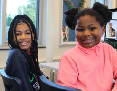 Two female students smiling in classroom