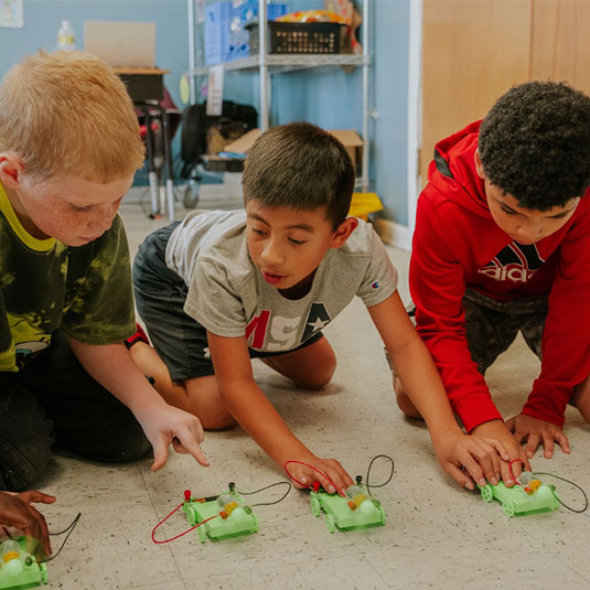 Young boys playing with toys on the ground together.