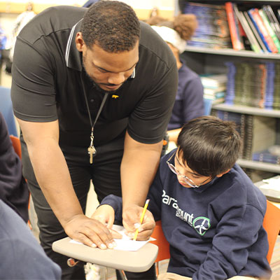 Male teacher helping student at their desk.