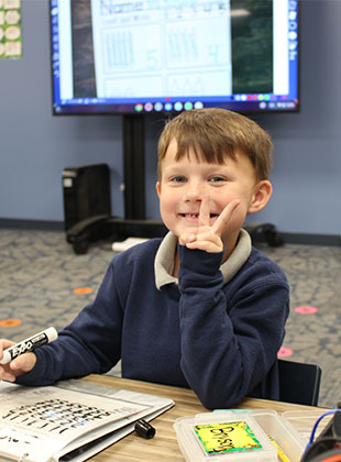 Young boy sitting at his table in the classroom