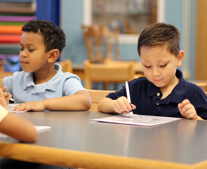 Young students working on school work at the classroom table.