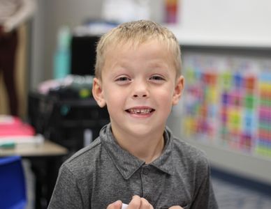 Elementary-aged boy smiling in classroom