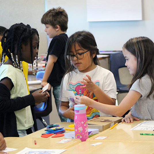 Young students working together at classroom table.