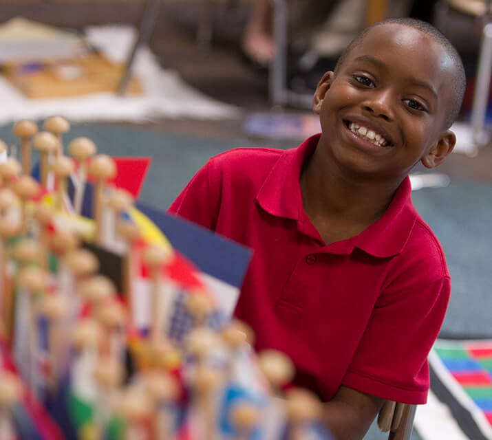 Innovation Network Schools student by flags in his classroom