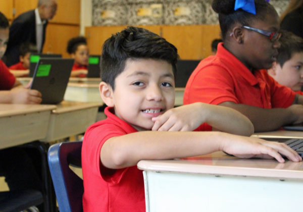 young boy sitting at desk in classroom