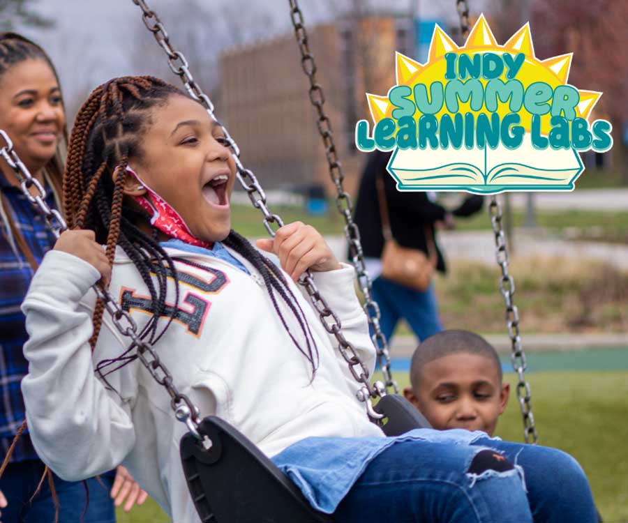 Little girl swinging on the playground with her family