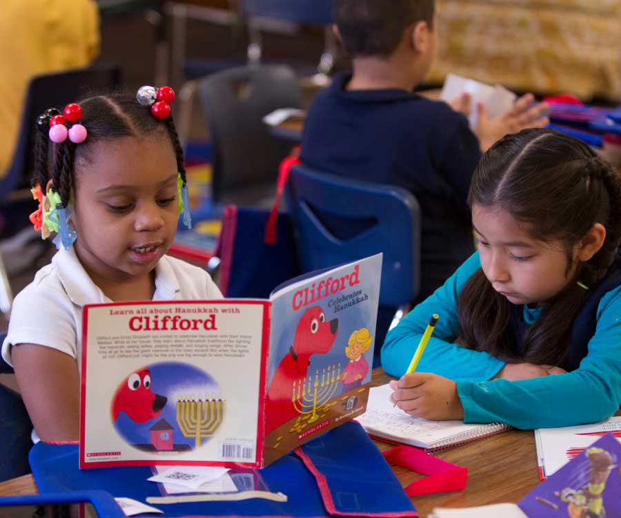 little girls in class reading and working on school work.