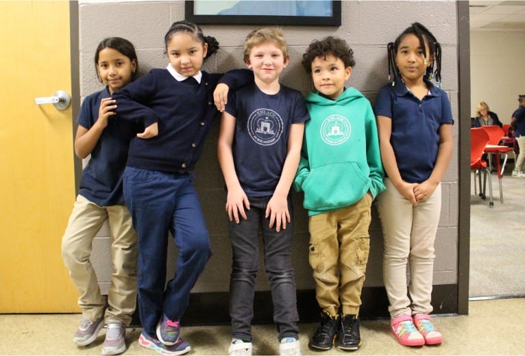 elementary children posting for group photo in school hallway