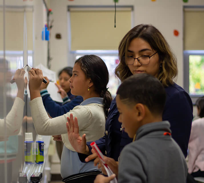 students at whiteboard with teacher