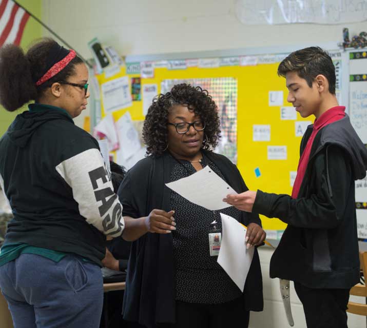 teacher reviewing paper with two students